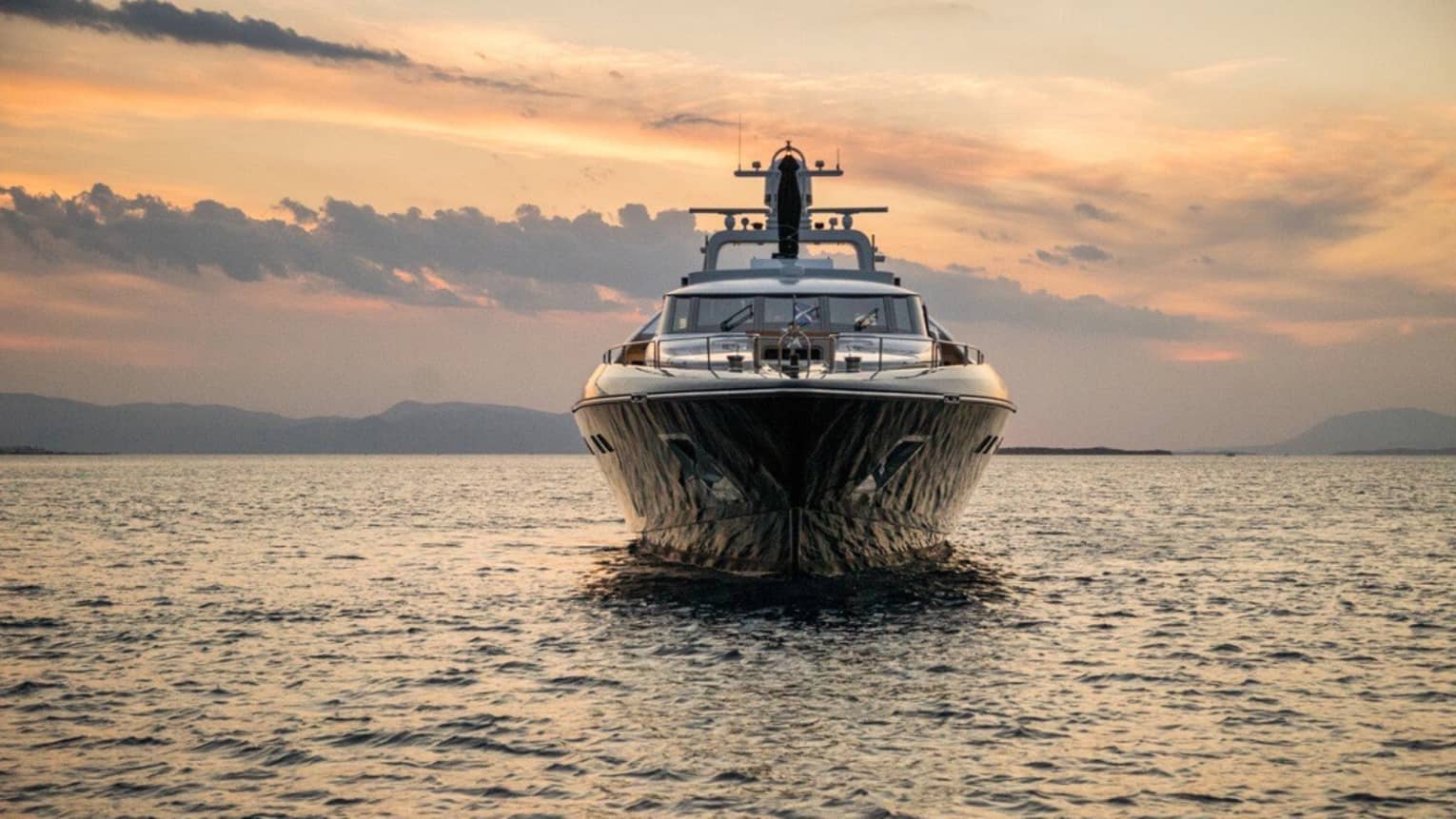 Yacht from bow as it sits in water at sunset