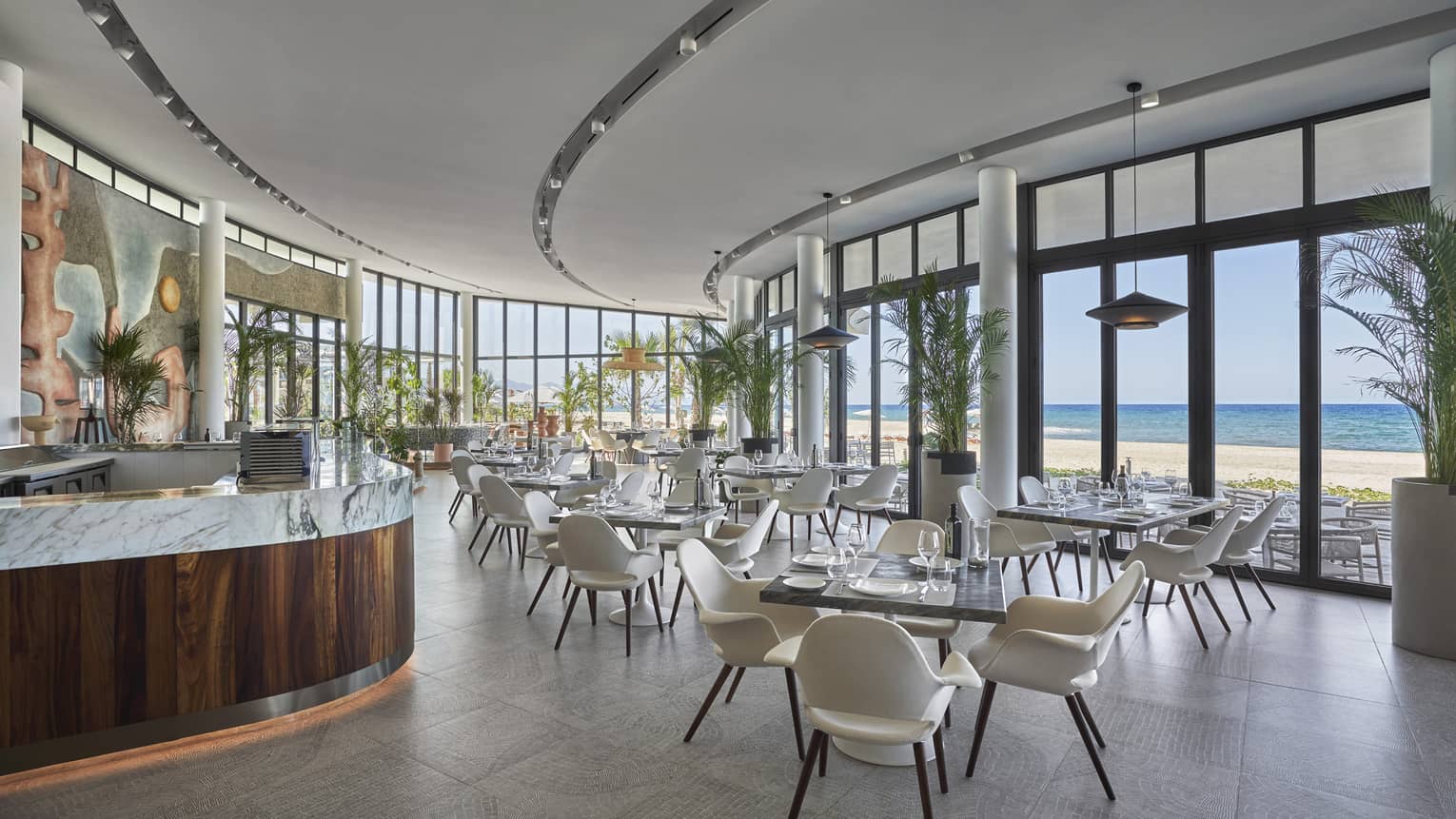 Milos contemporary curved dining room with square tables and white chairs, water views