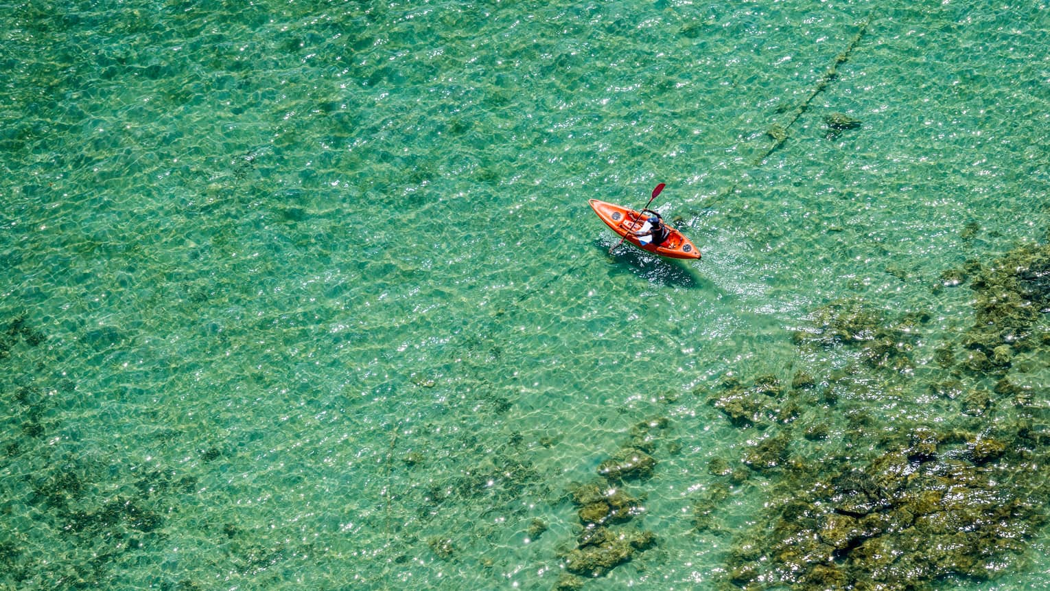 Aerial view of red kayak over turquoise lagoon