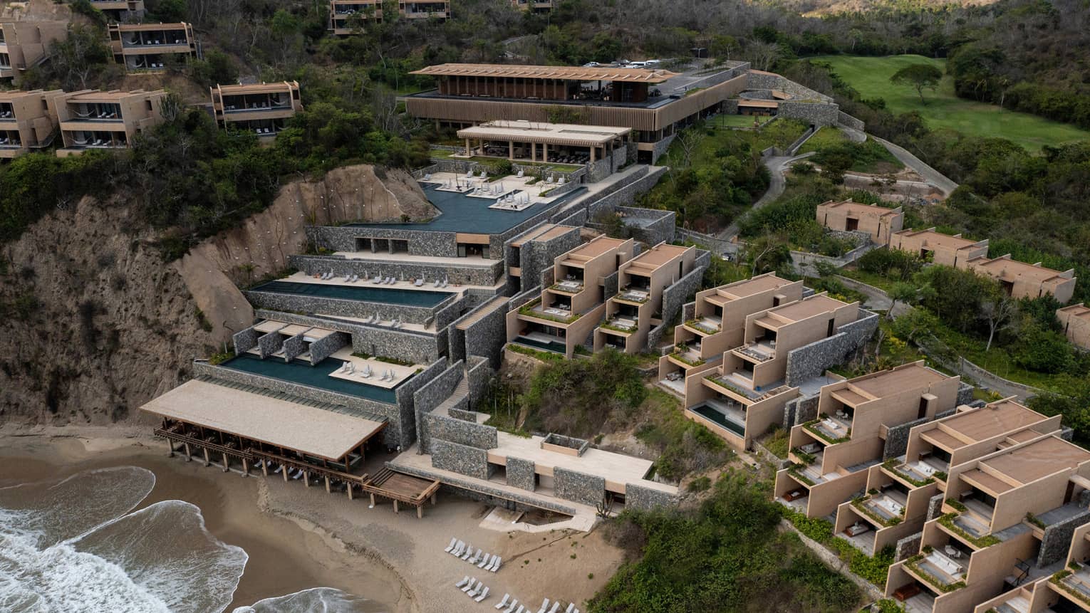 A property up against a cliff or mountain side on a beach.