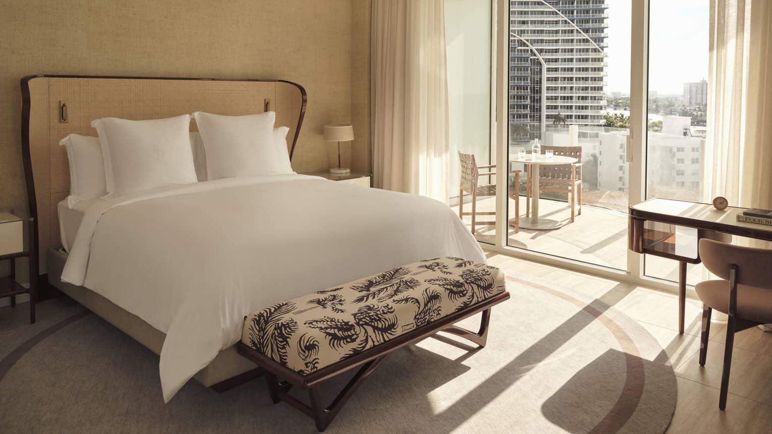 Hotel room with king bed, bench, glass doors to balcony