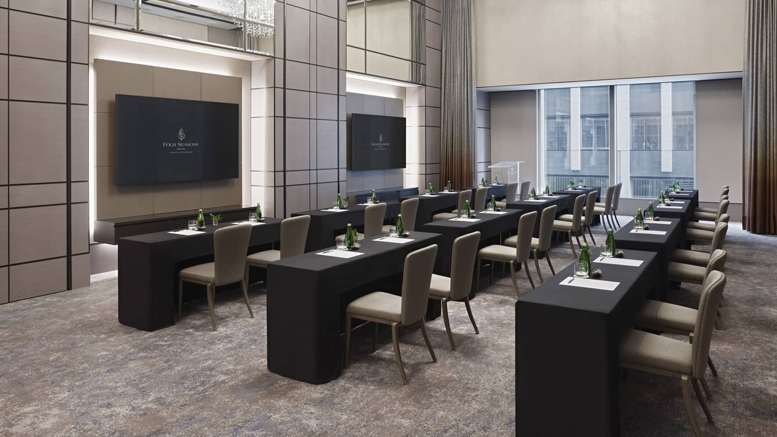 Meeting room set classroom-style with double chandeliers, black linens and two presentation screens 