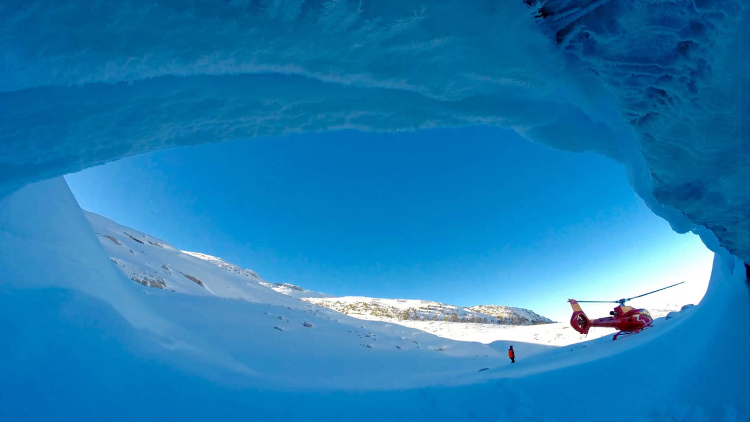 Helicopter against striking blue sky at opening of ice cave