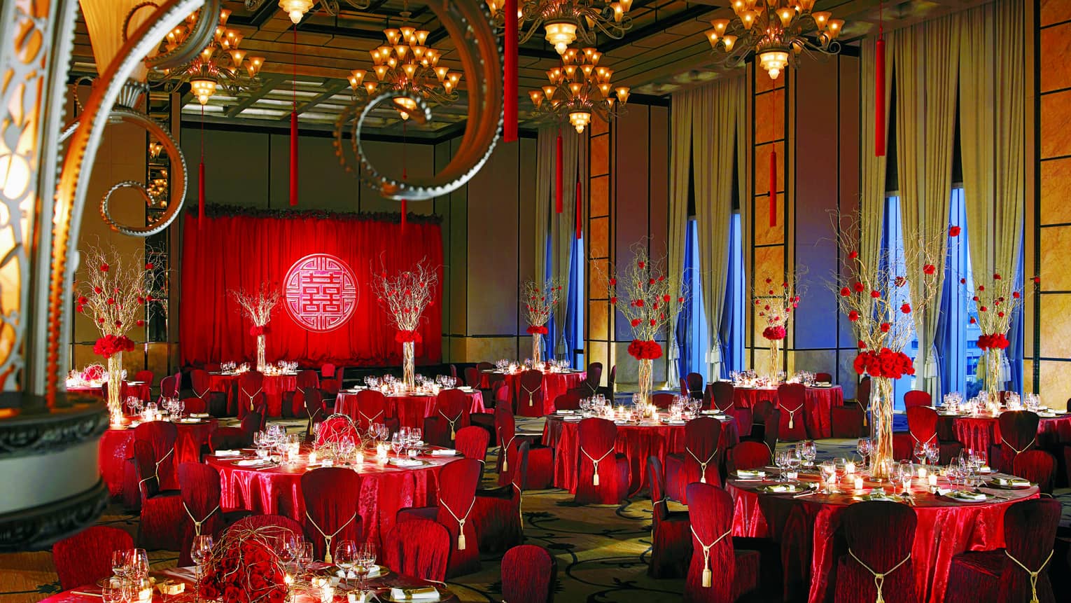 Elegant wedding banquet hall with red table linens and flower centrepieces, high ceilings, chandeliers