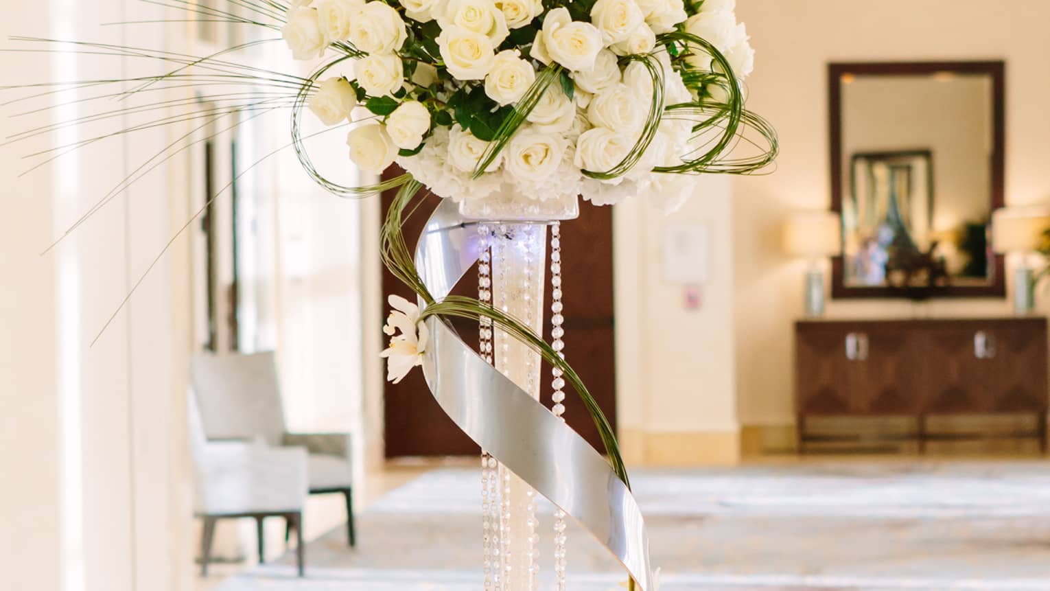 Wedding accent table with rows of name cards, tall white flower arrangement with ribbon