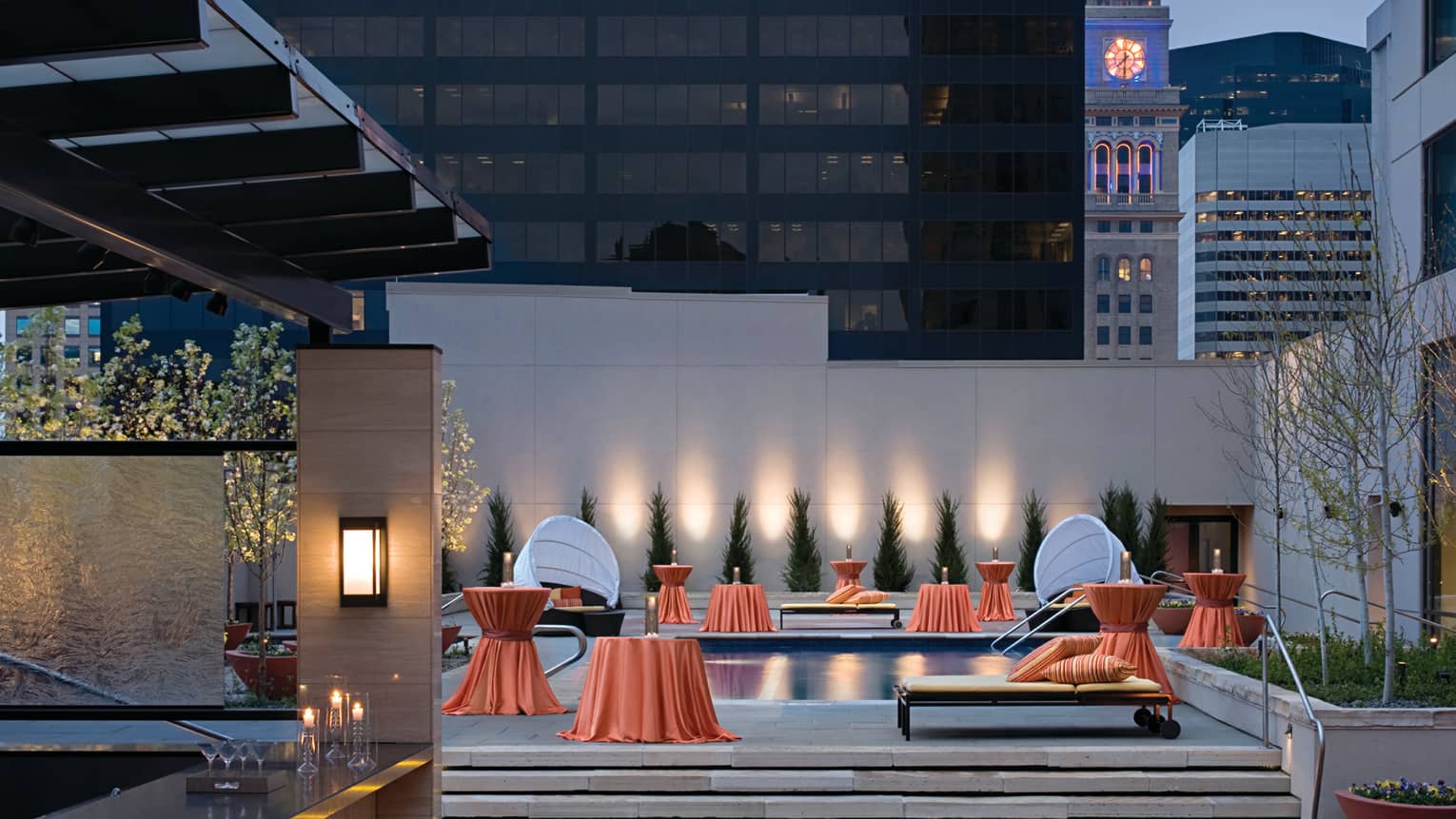 Rooftop bar, orange linens over small tables around outdoor pool