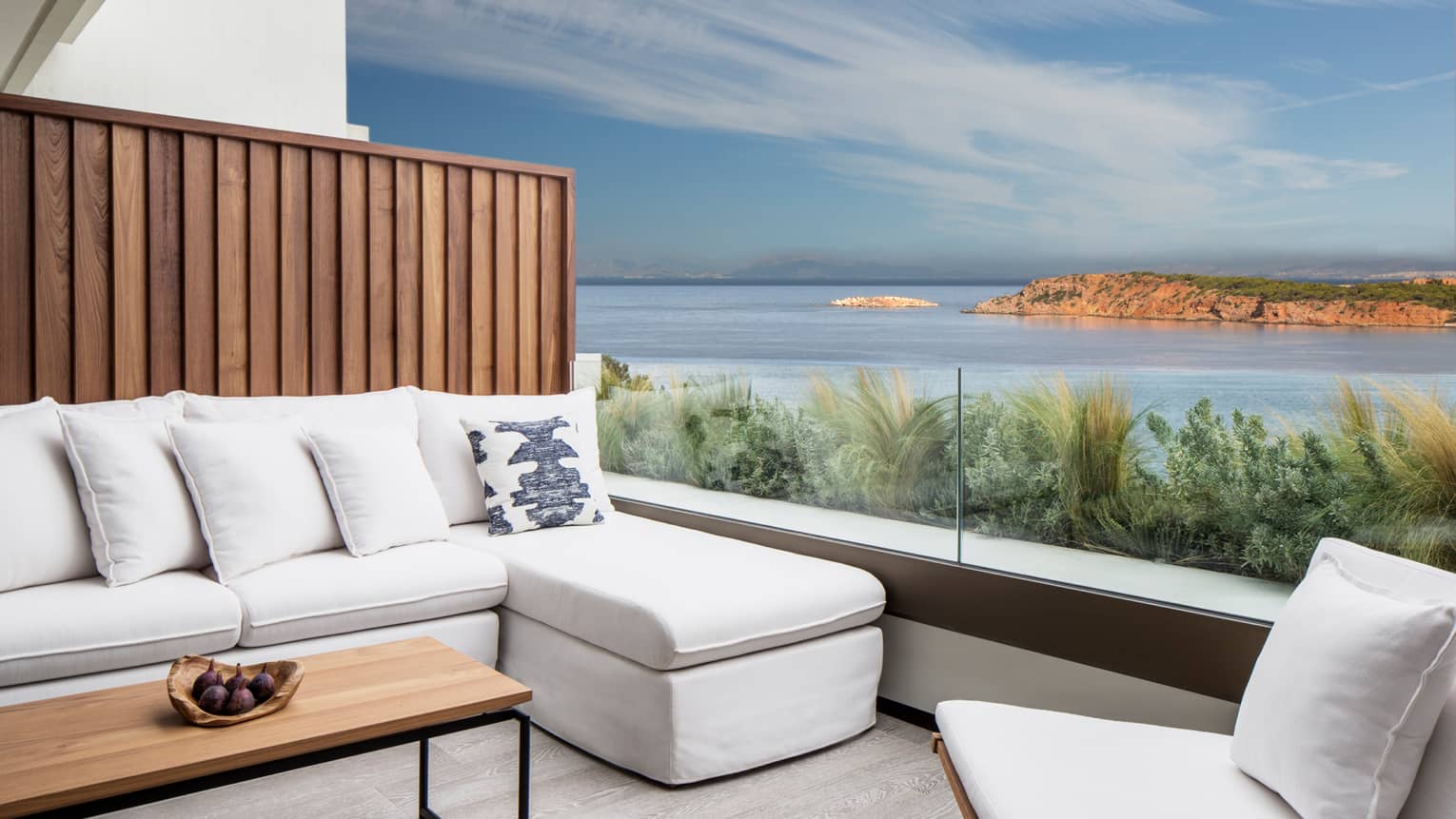 Outdoor terrace with white sofa and accent chair, rectangular coffee table, ocean views