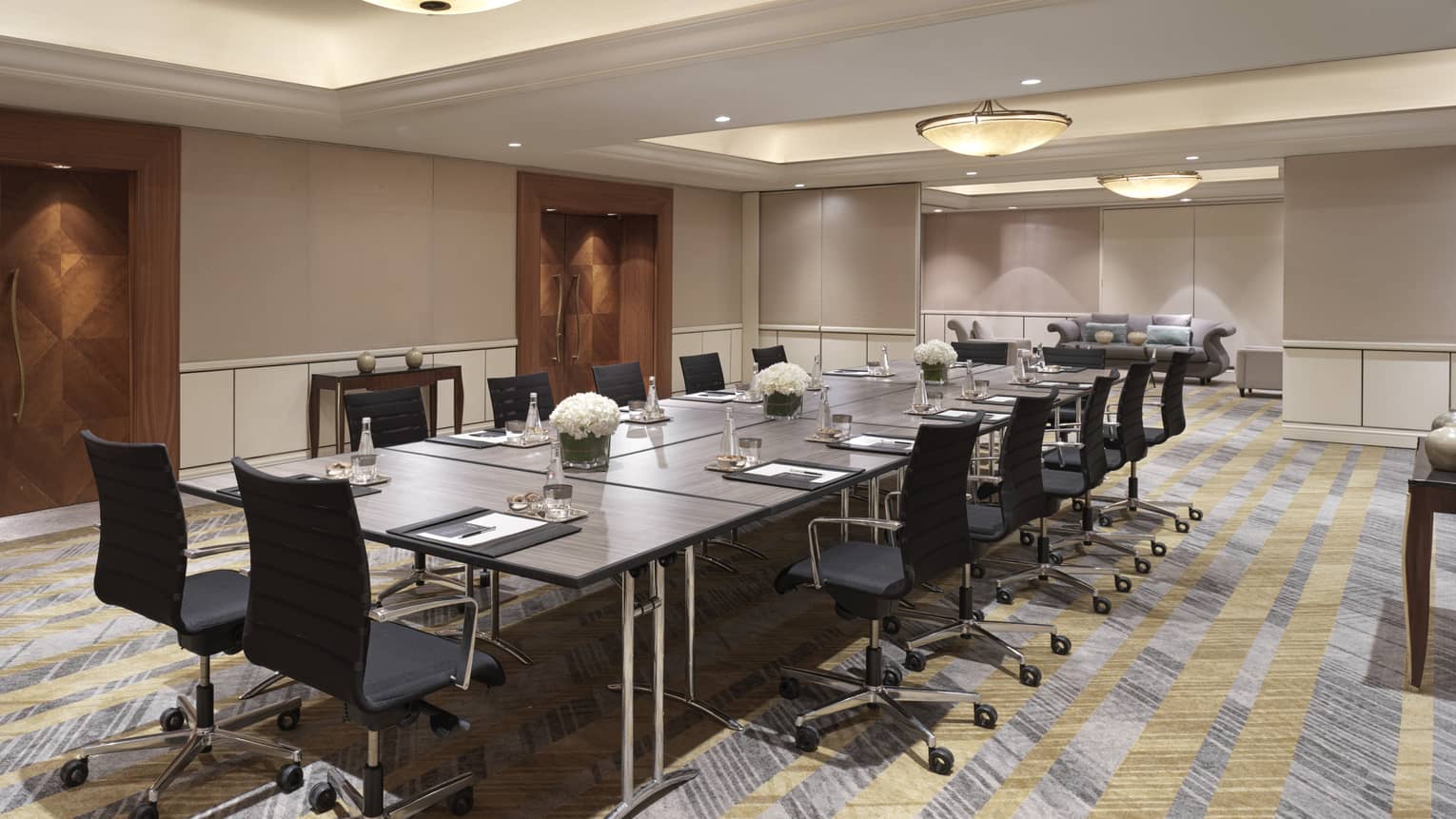 A boardroom with a long black table, and black office chairs.