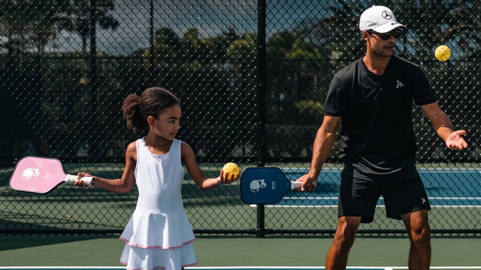 Two guests outdoors playing pickleball.