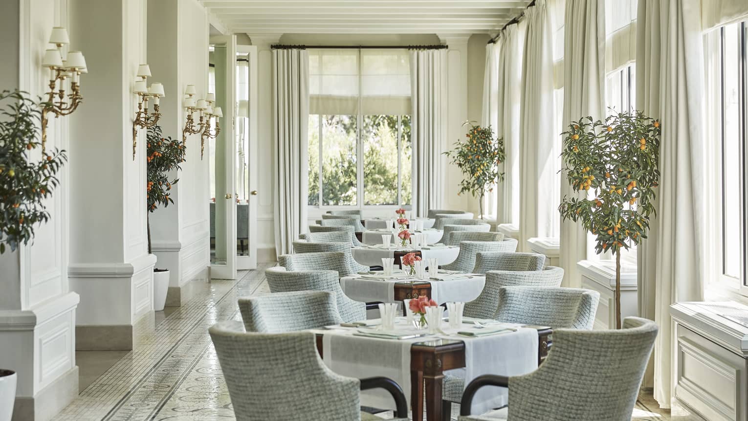 Grey chairs around tables in sunny Le Veranda dining room