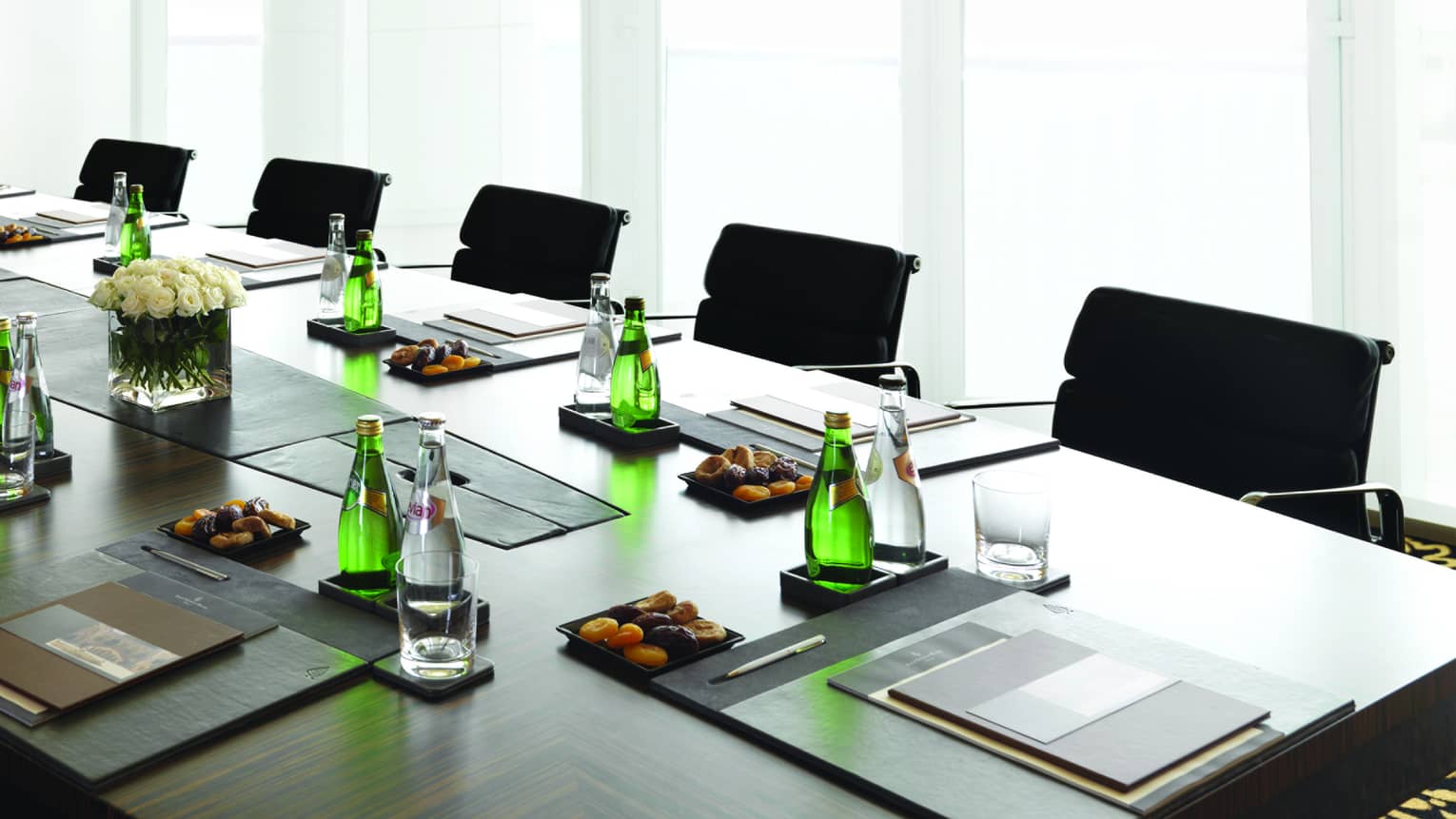 Boardroom meeting table set with water, dried apricots, menus by sunny window