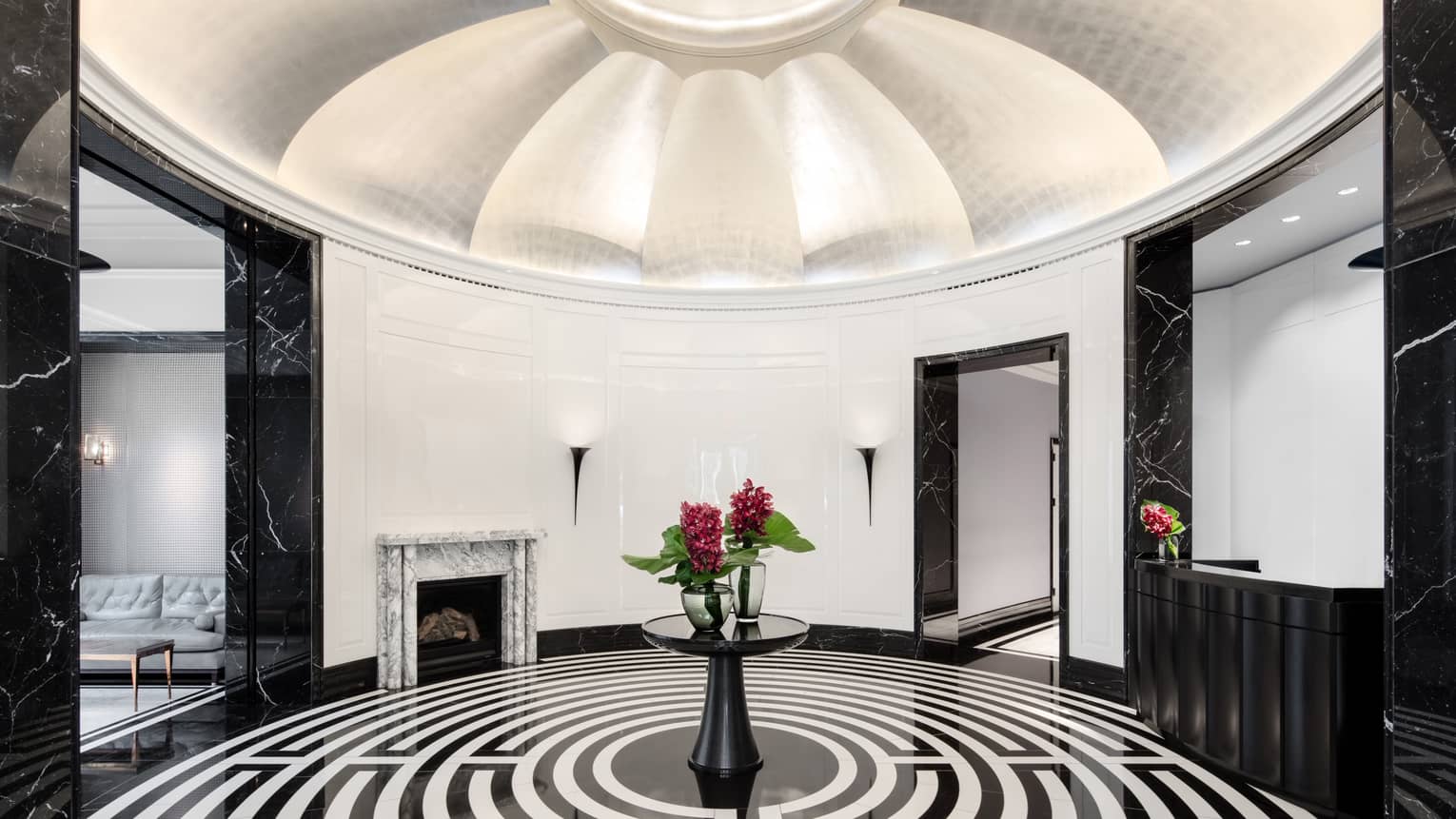 Dramatic white dome ceiling over rotunda with black-and-white maze flooring, red flowers on table