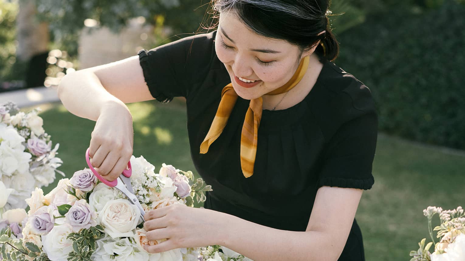 A four seasons staff adds the final touches to a floral arrangement on a banquet table