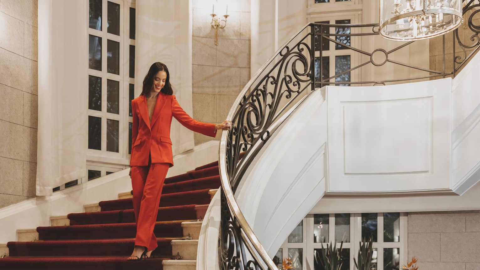 A woman in a red suit walking down stairs.