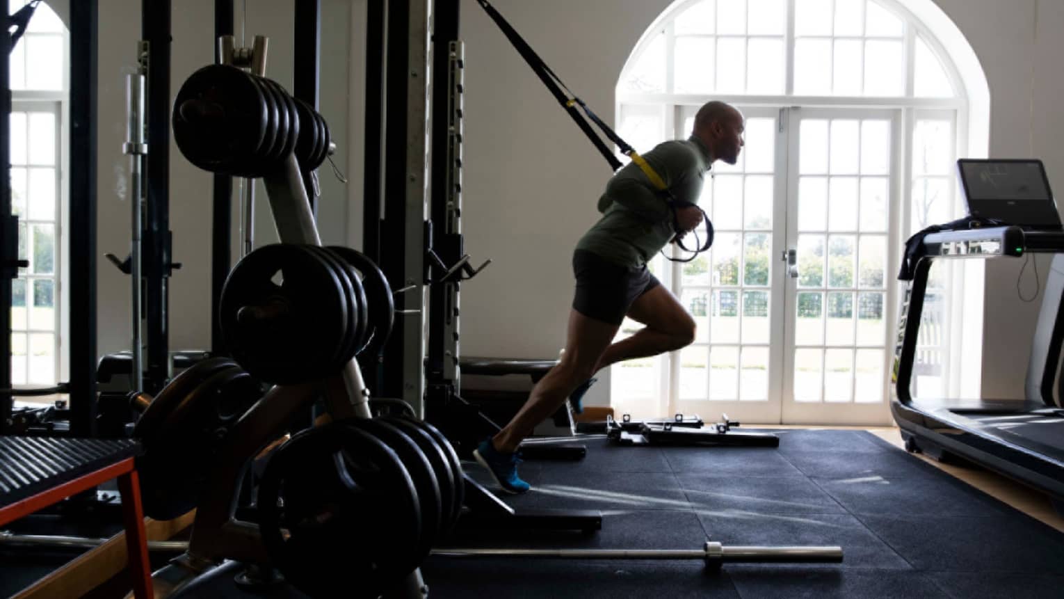 Silhouette of man leaning forward, pulling weights on large machine in Fitness Centre