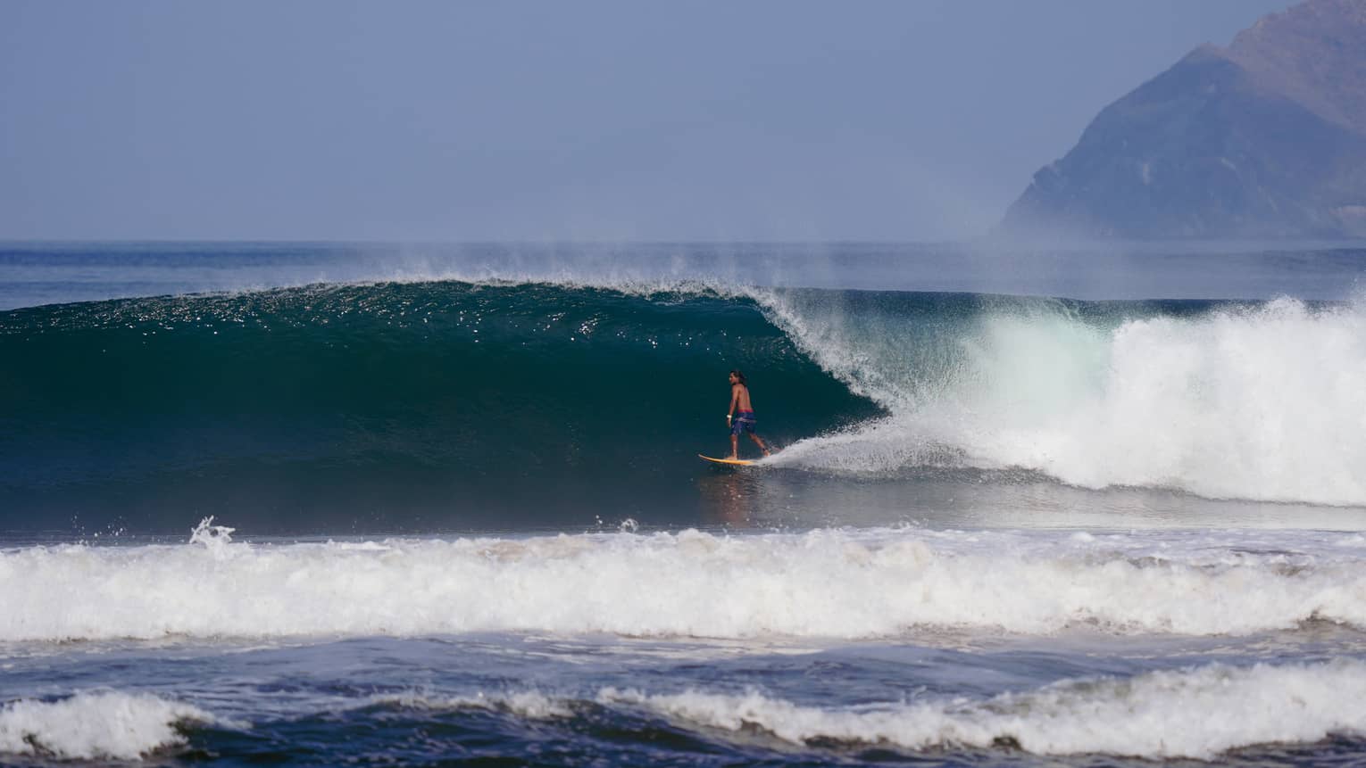 Man surfing under a large wave