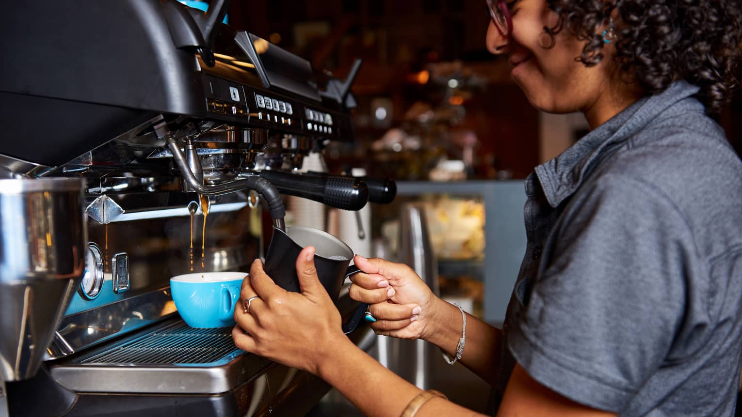 Smiling barista makes Big Island Coffee Roasters coffee at espresso machine