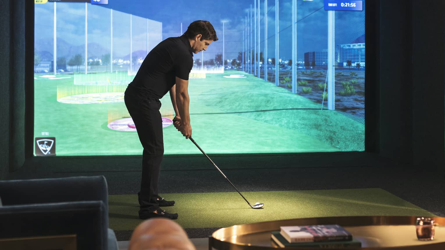 Man with golf club stands in front of screen showing Virtual Fairway