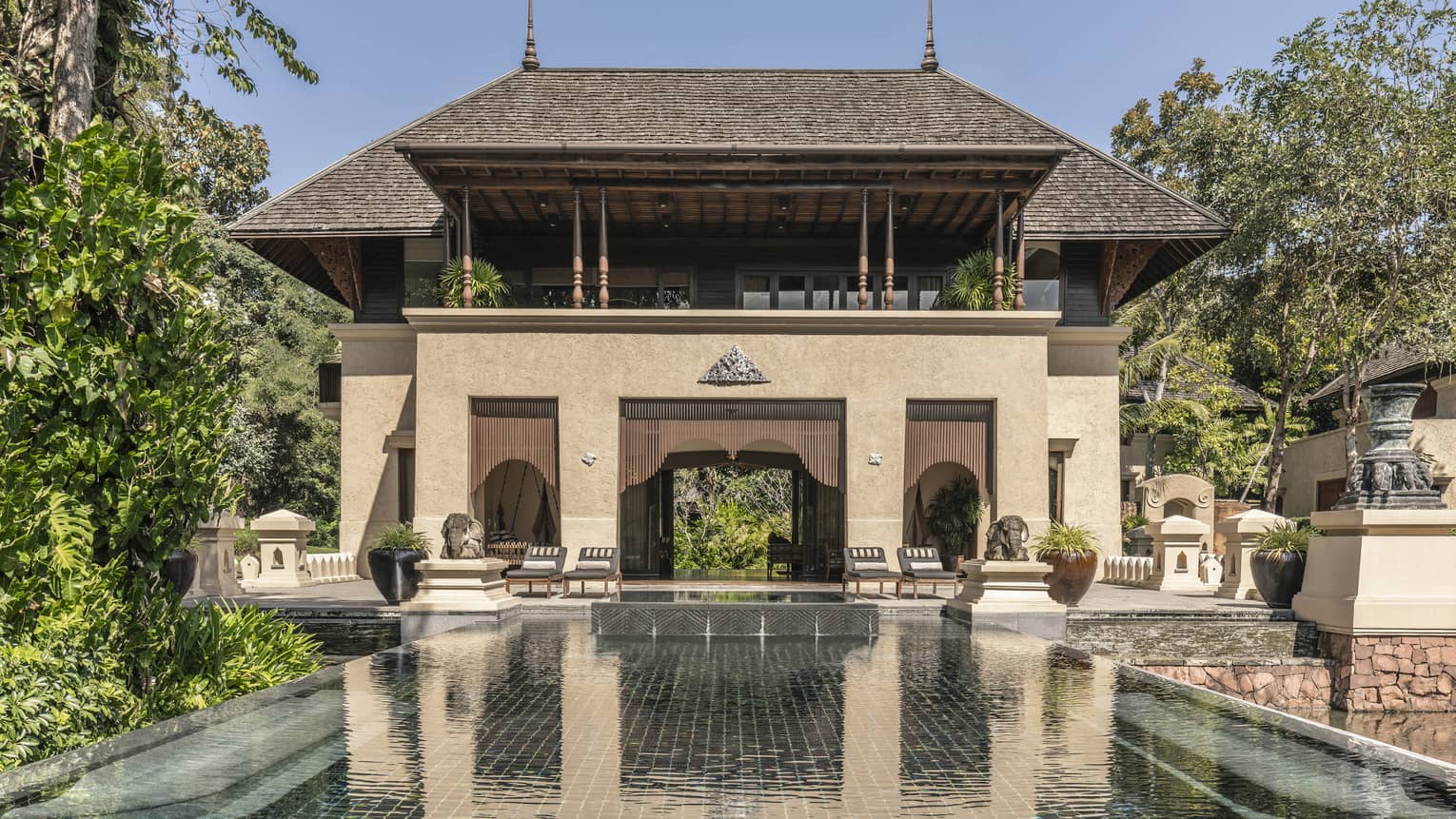 A large brown villa with a pool extending out from it.