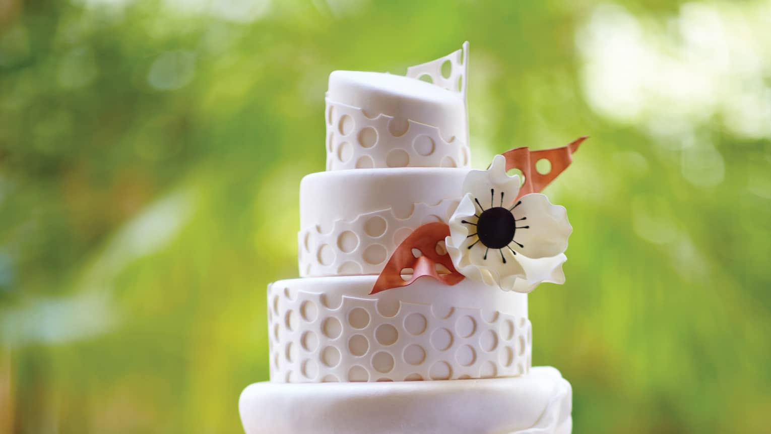 Small four tiered wedding cake decorated with fondant pattern, flower