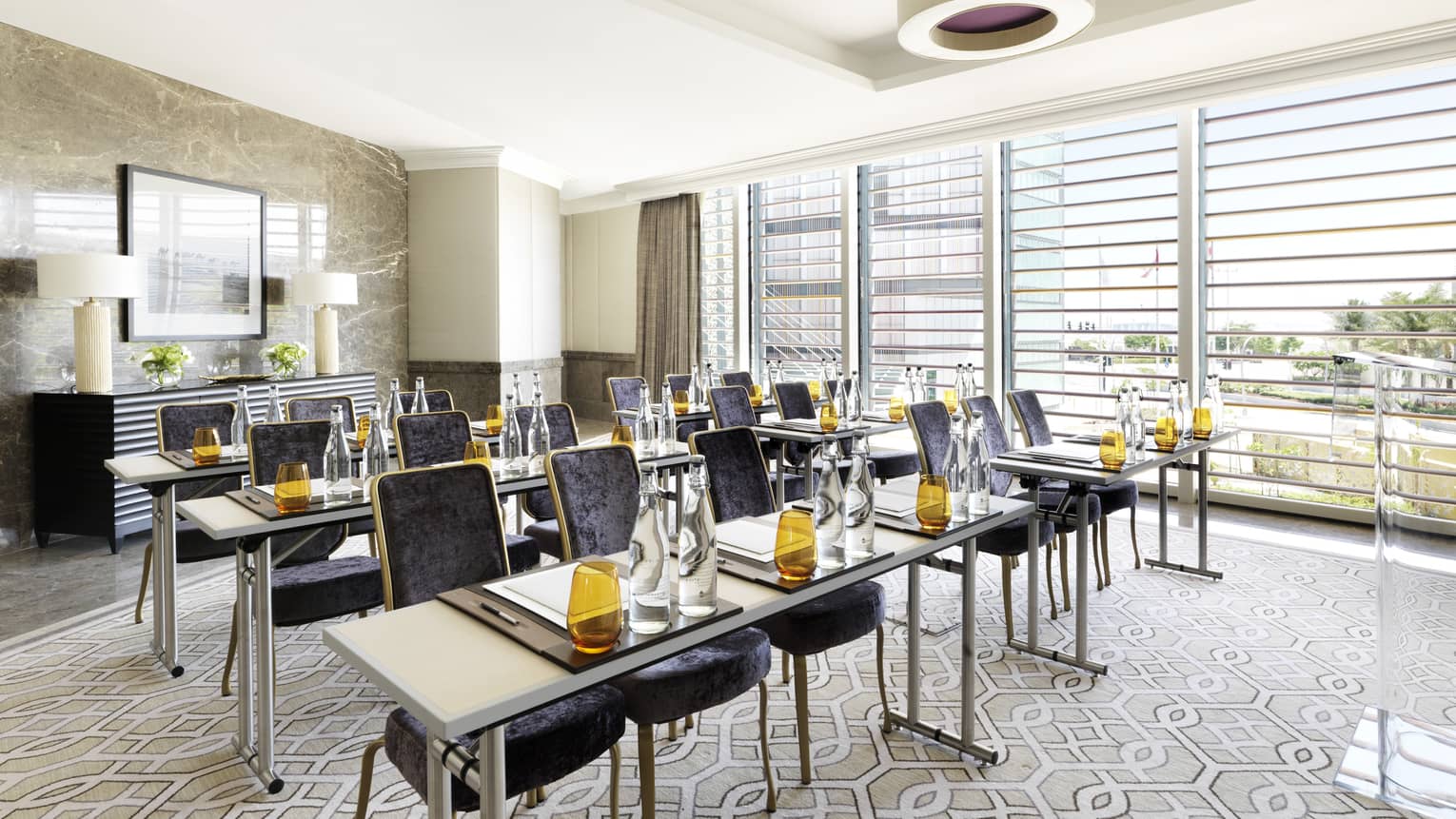 Three rows of modern tables with amber glasses, velvet chairs in the Al Maqtaa Meeting Room