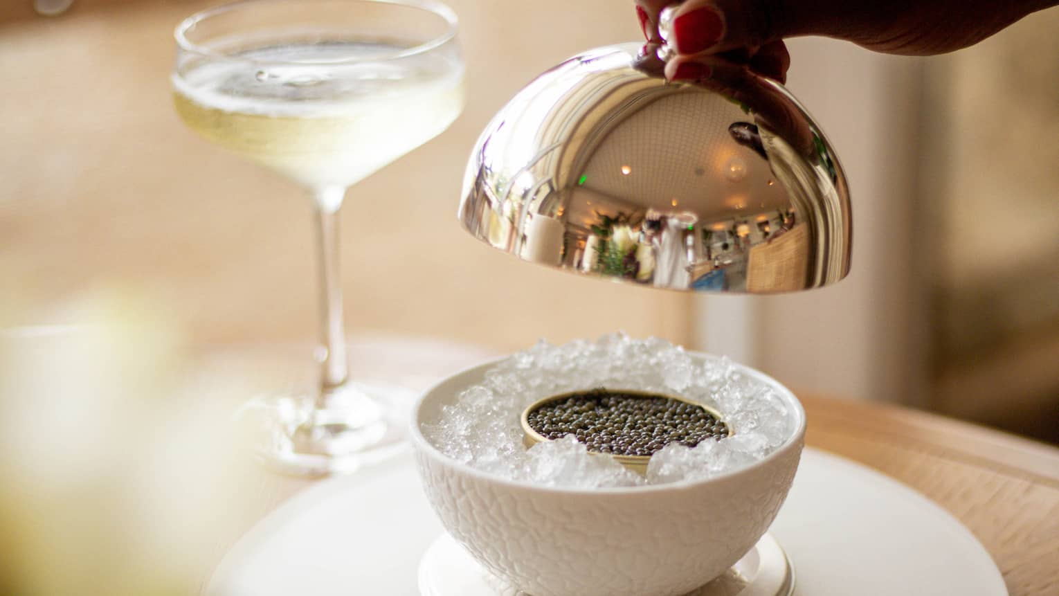 Caviar on ice next to a glass of wine.