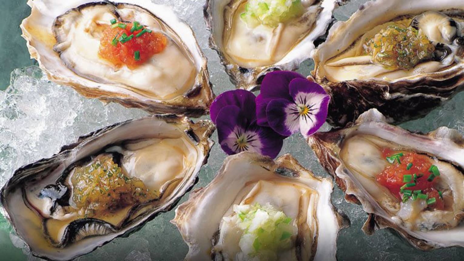 Raw oysters with Nobu Sauces and purple flowers on ice platter
