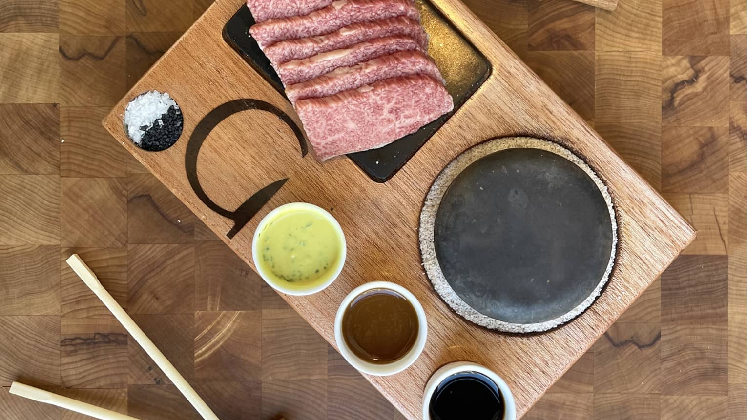 Wagyu steak and sauces on a wooden tray.
