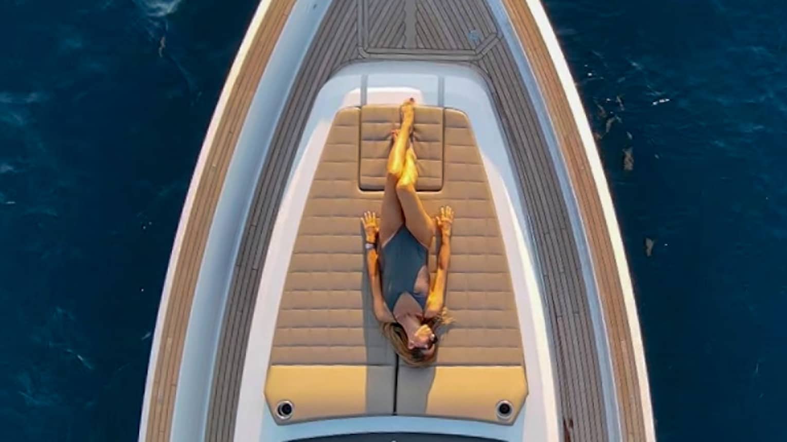 View from above of woman sunbathing on front deck of yacht.