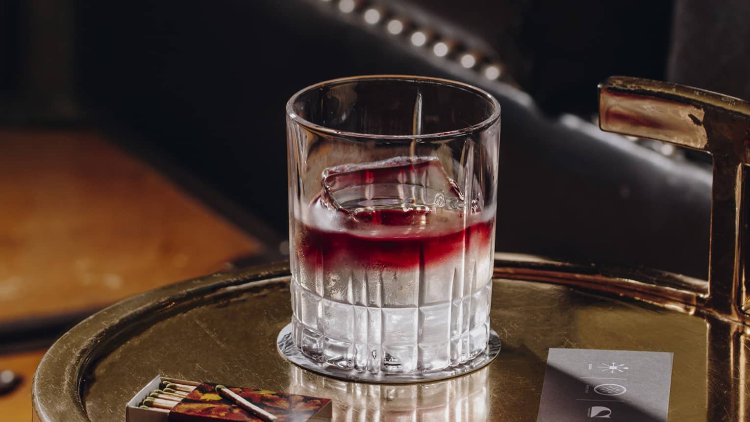 A red and clear cocktail on a tray.