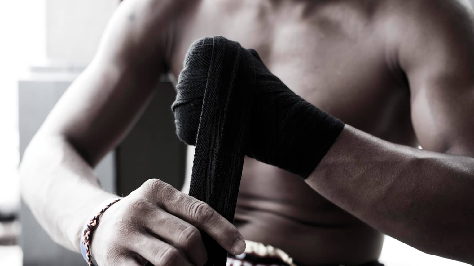 Close-up of Muay Thai boxer wrapping black boxing tape around hands