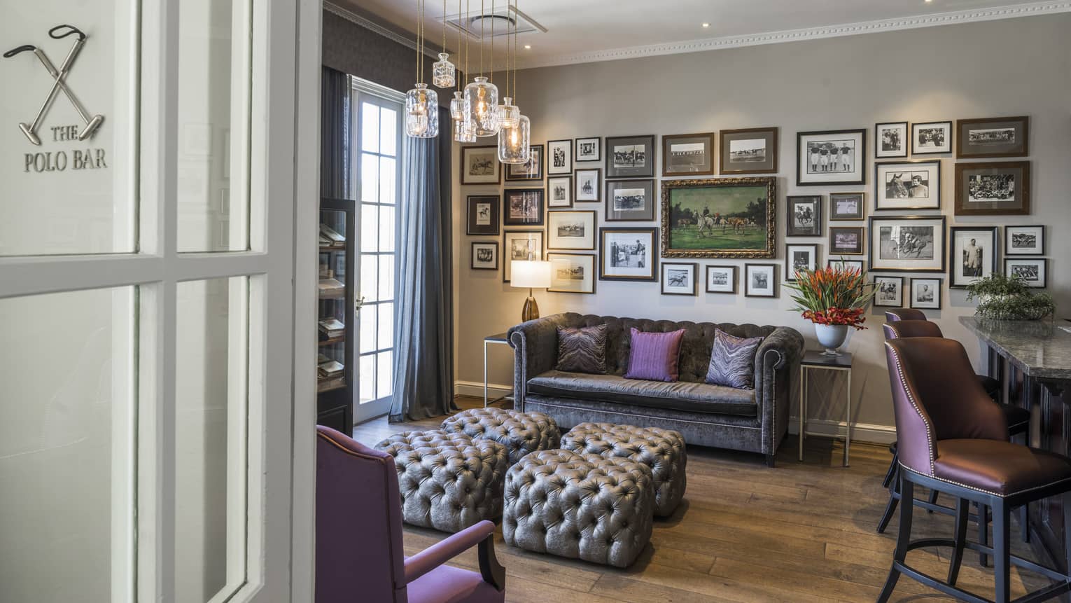 Polo Bar seating area with puffed ottomans, sofa under wall with framed pictures