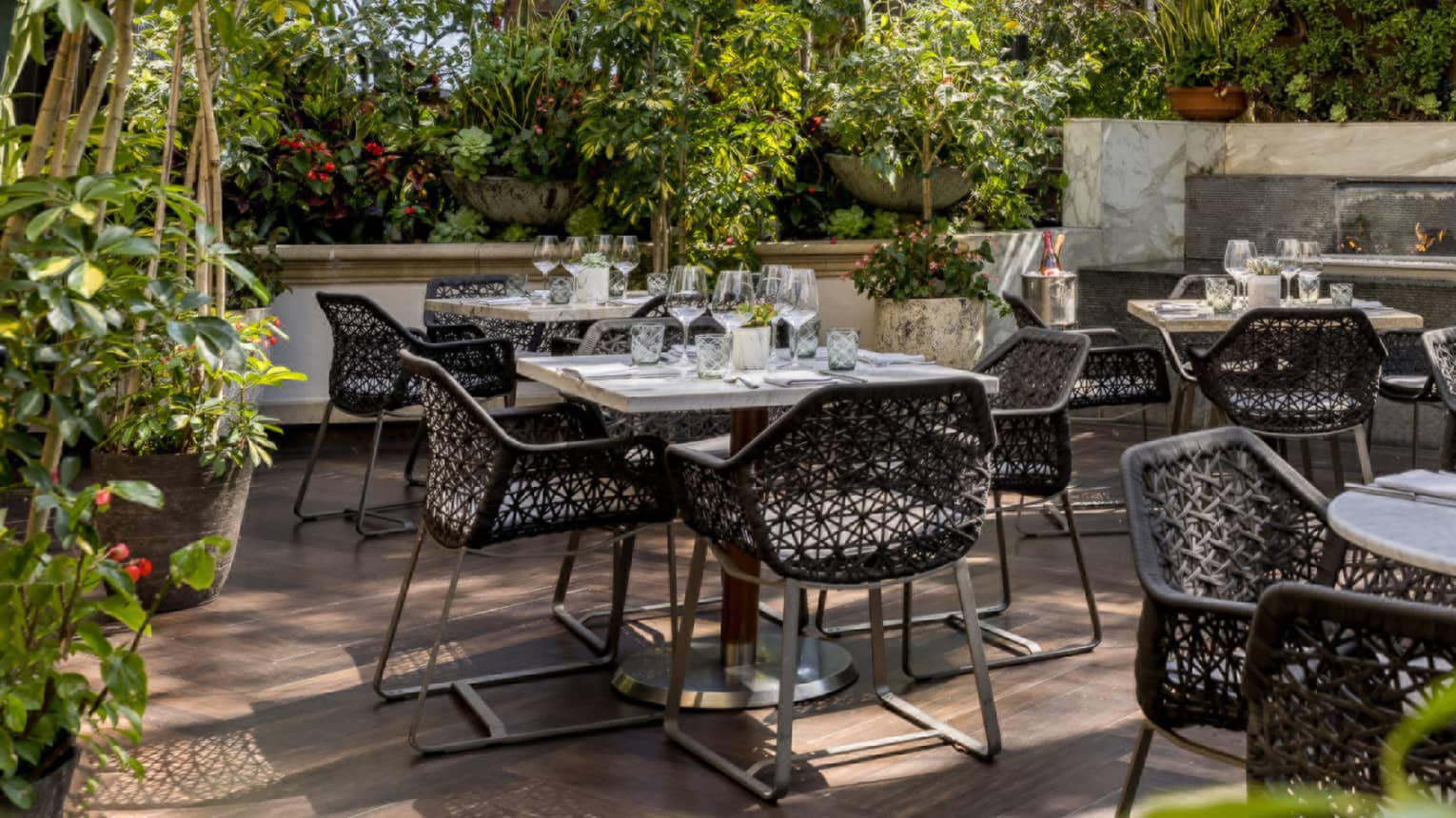 A courtyard area with round table and metal chairs surrounded by plants.