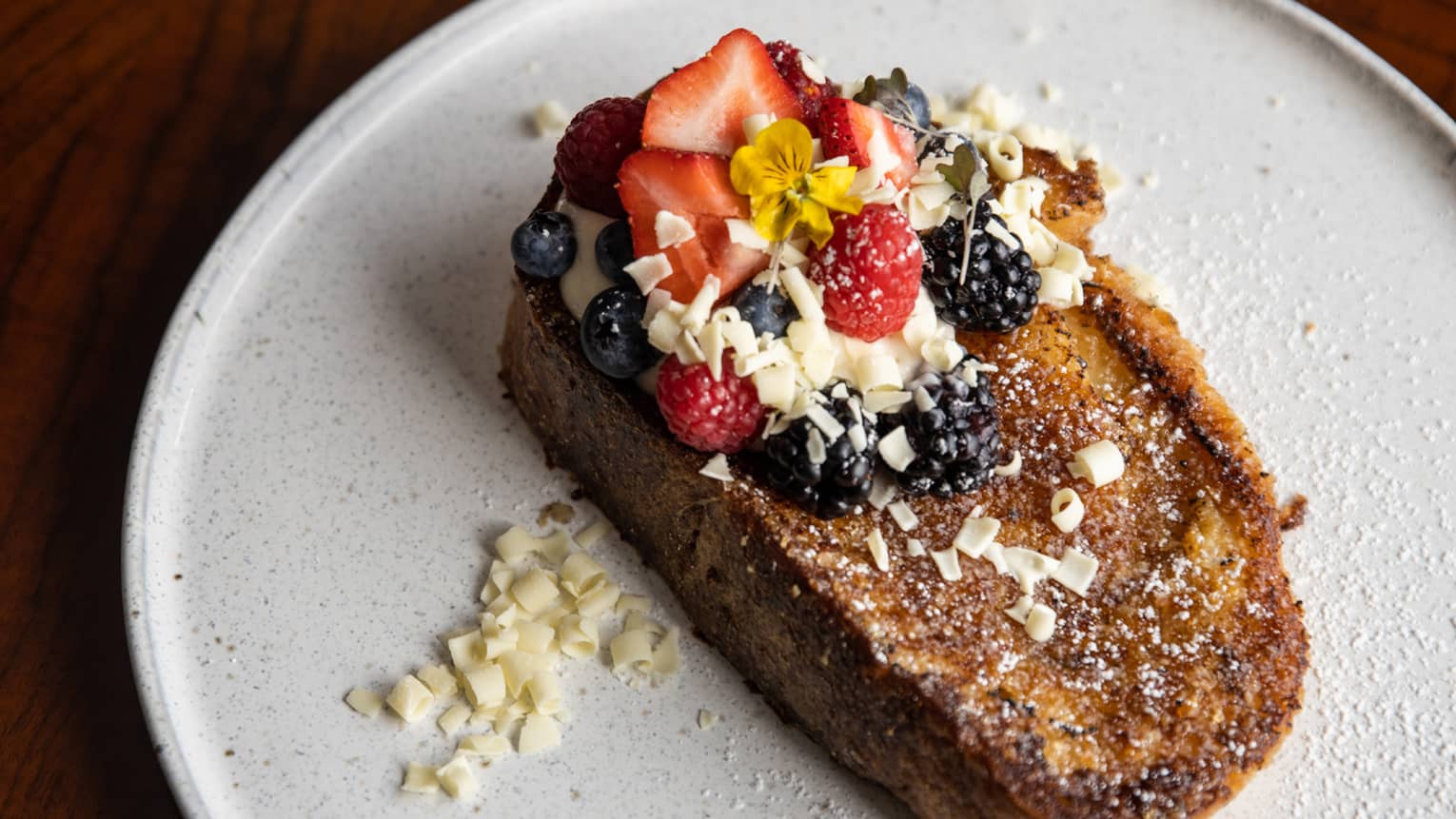 Thick piece of French toast topped with fresh berries, cream