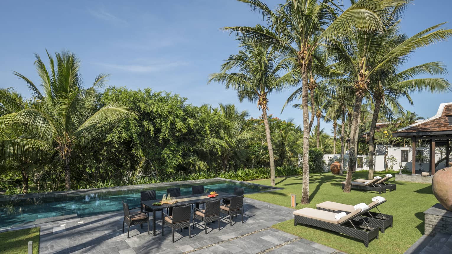 Three-Bedroom Hilltop Residence pool area with dining table, lounge chairs, palm trees and sunshine