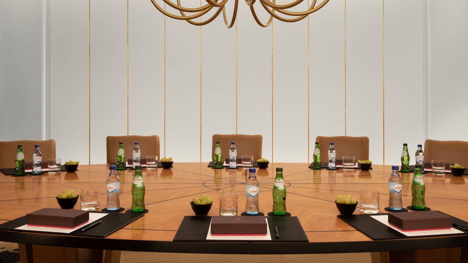  Close-up of Boardroom with chandelier over circular wooden table and brown leather parsons chairs 