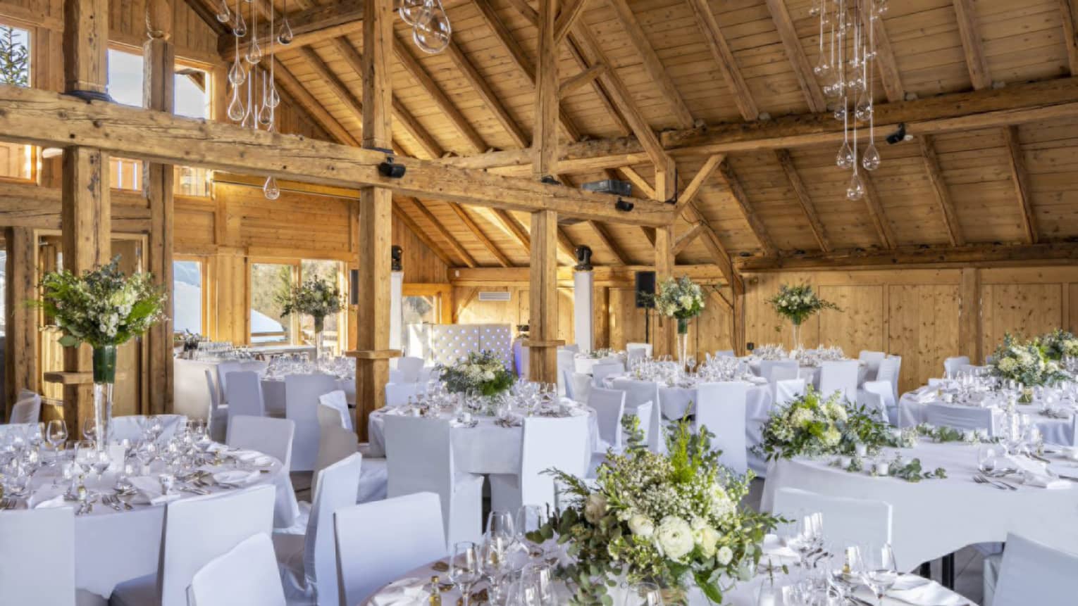 All-white wedding reception setup in Alpine chalet with tall wooden ceilings