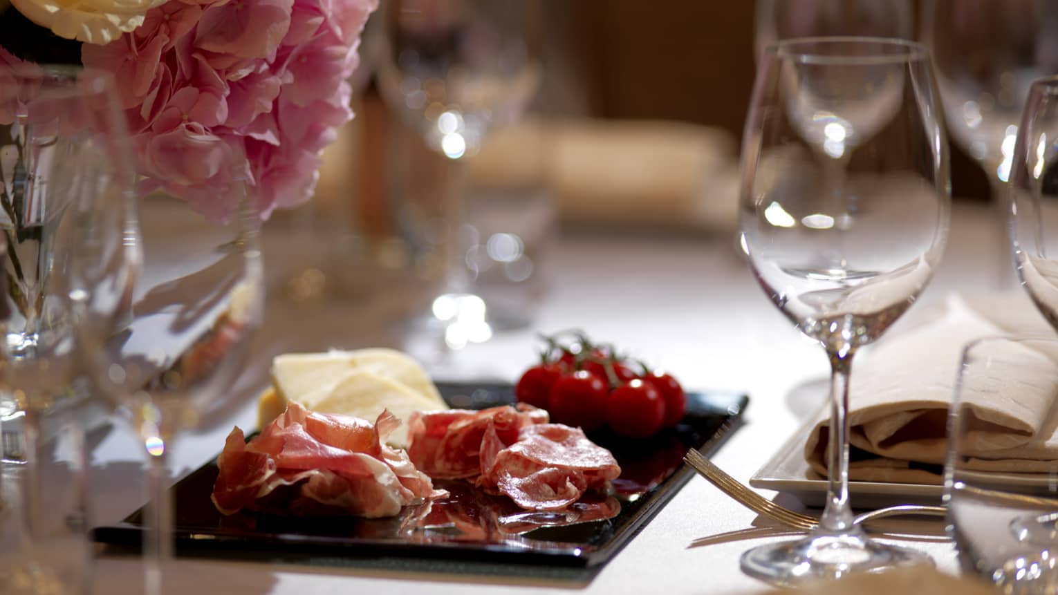 Close-up of small charcuterie platter with cured meat, tomato, cheese on banquet table