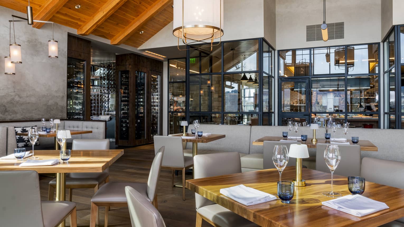 Restaurant with square wooden tables, light grey chairs, and vaulted ceiling