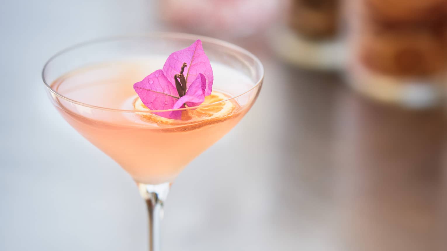 Martini cocktail with small pink flower on bar