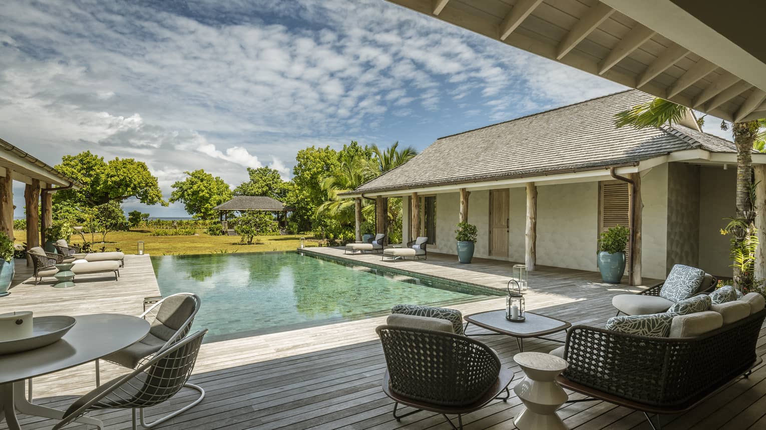 Rectangular pool of villa, surrounded by a wooden deck and lounge seating