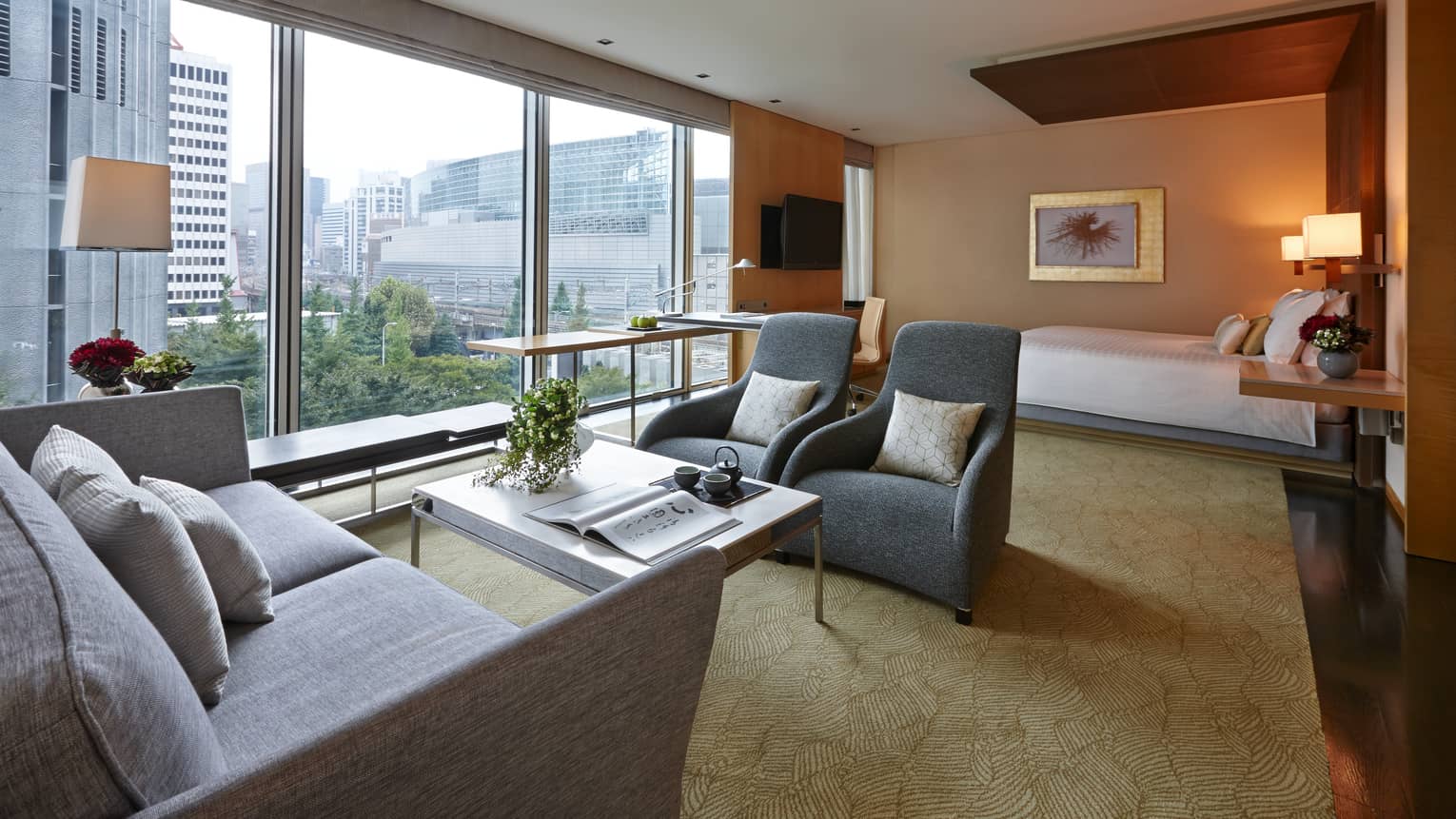 Hotel suite sofa, modern armchairs and table by sunny floor-to-ceiling window