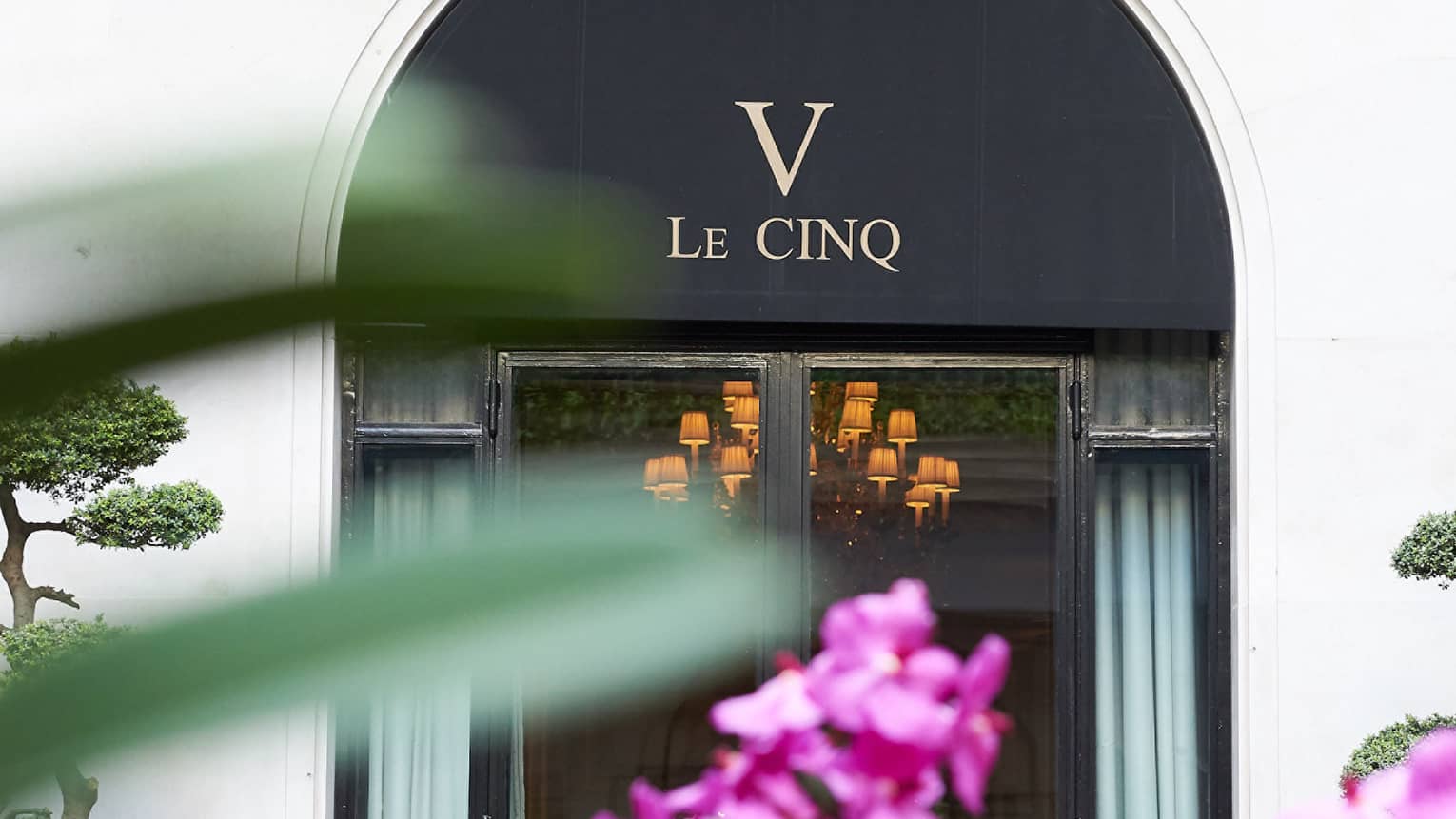 Le Cinq awning over entrance past purple flowers