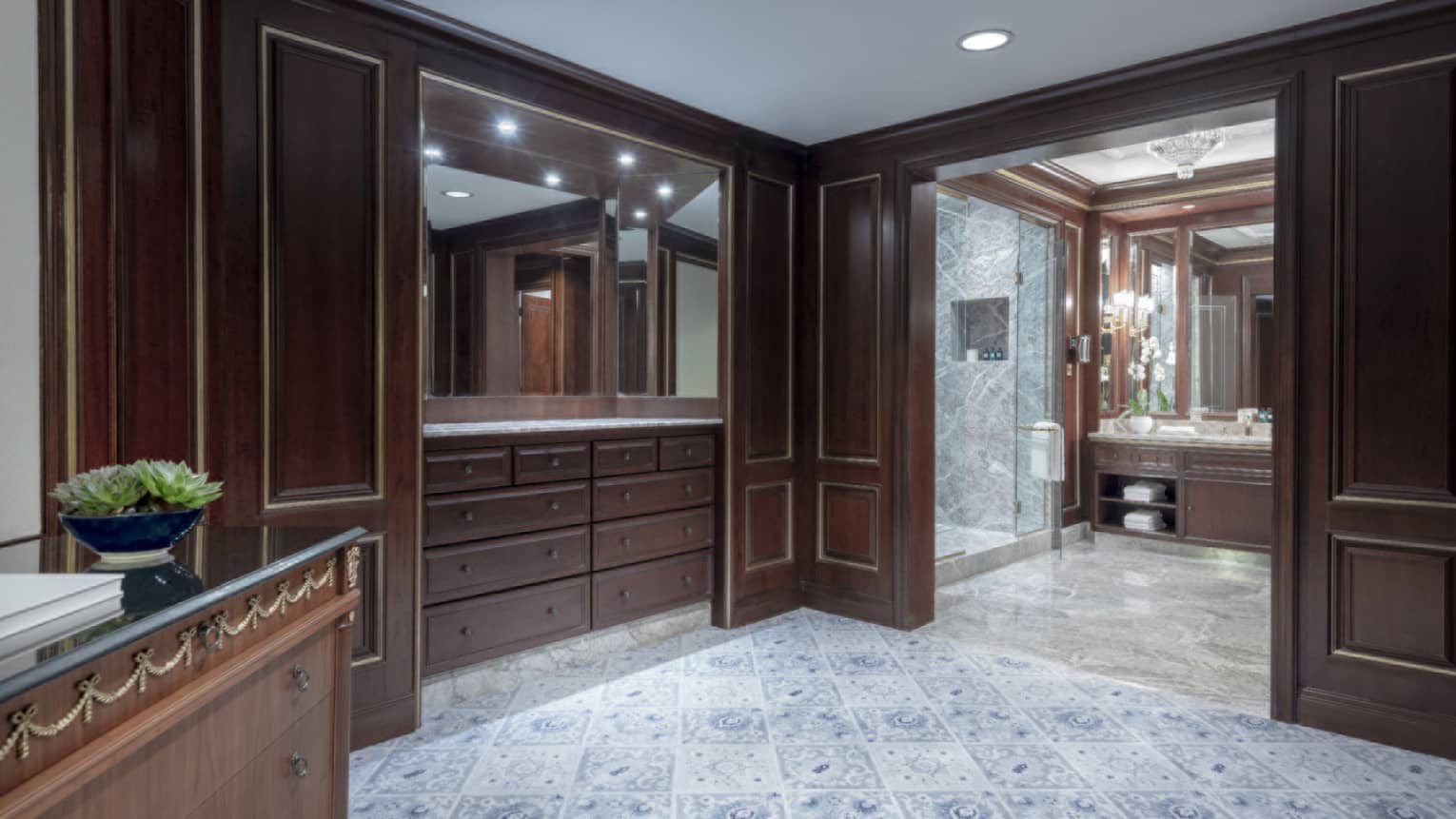 Dark wooden built-in closet shelving on a grand hotel suite, with double doors opening to bathroom
