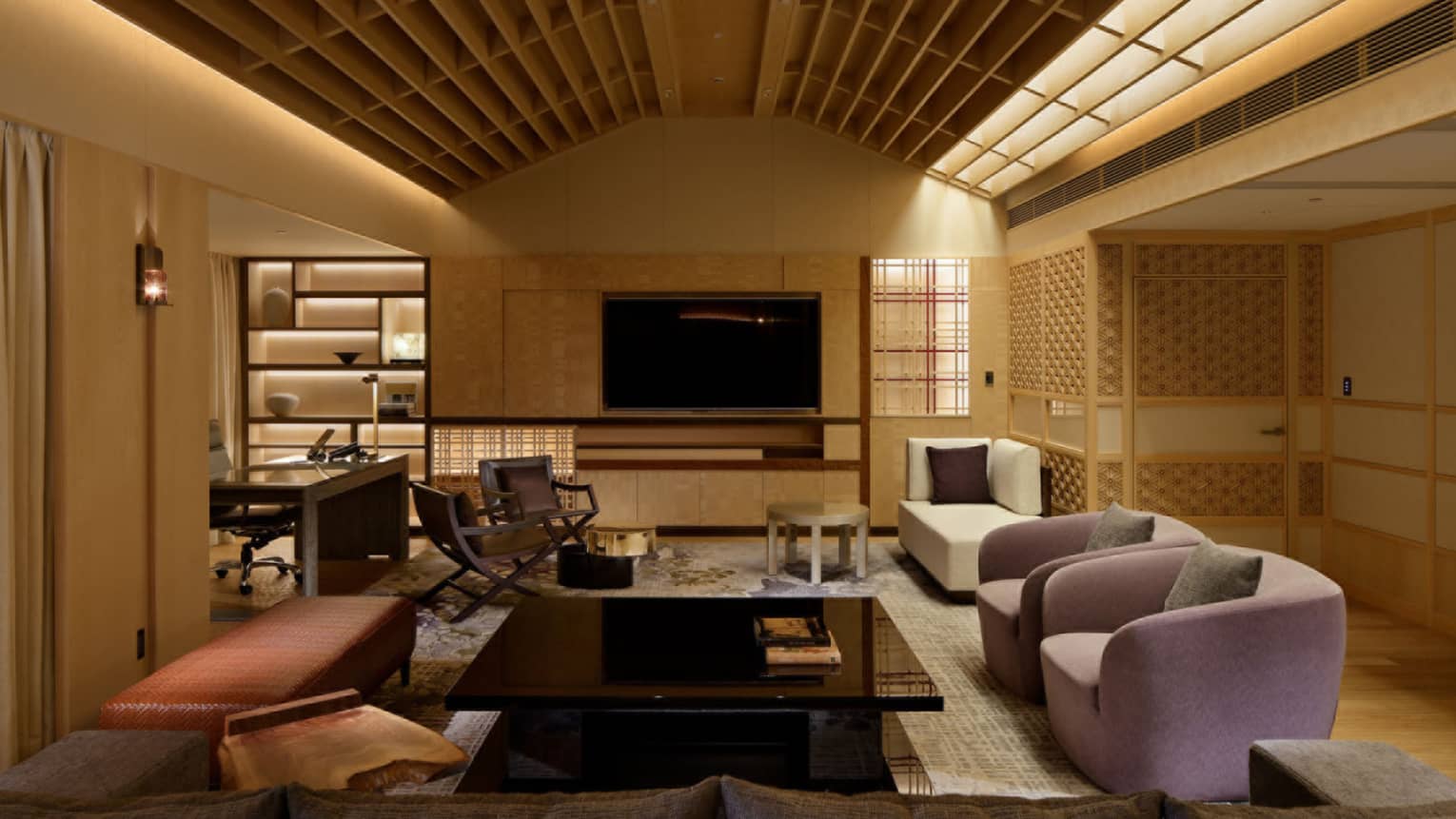 Japanese-stlye living room with illuminated wooden beam ceiling, sofa, two arm chairs, large square coffee table and TV