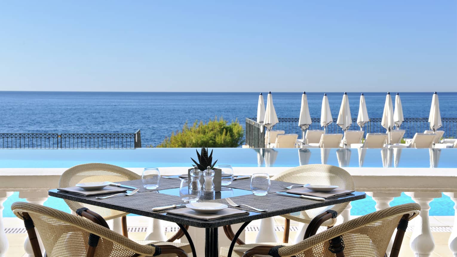 Club Dauphin patio table, chairs by outdoor swimming pool, blue sea