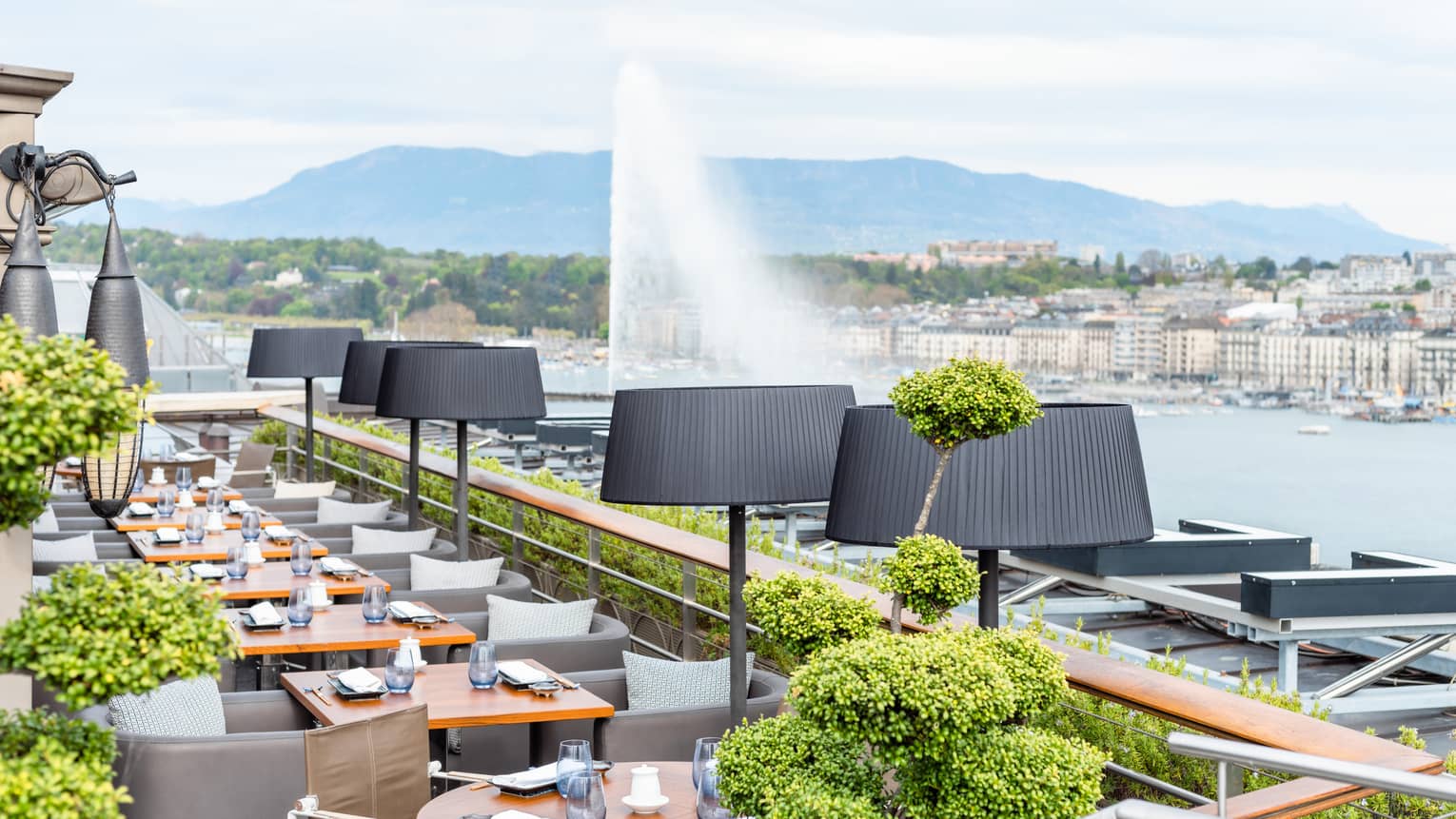 Restaurant terrace lined with tables overlooking Lake Geneva's Jet d'Eau
