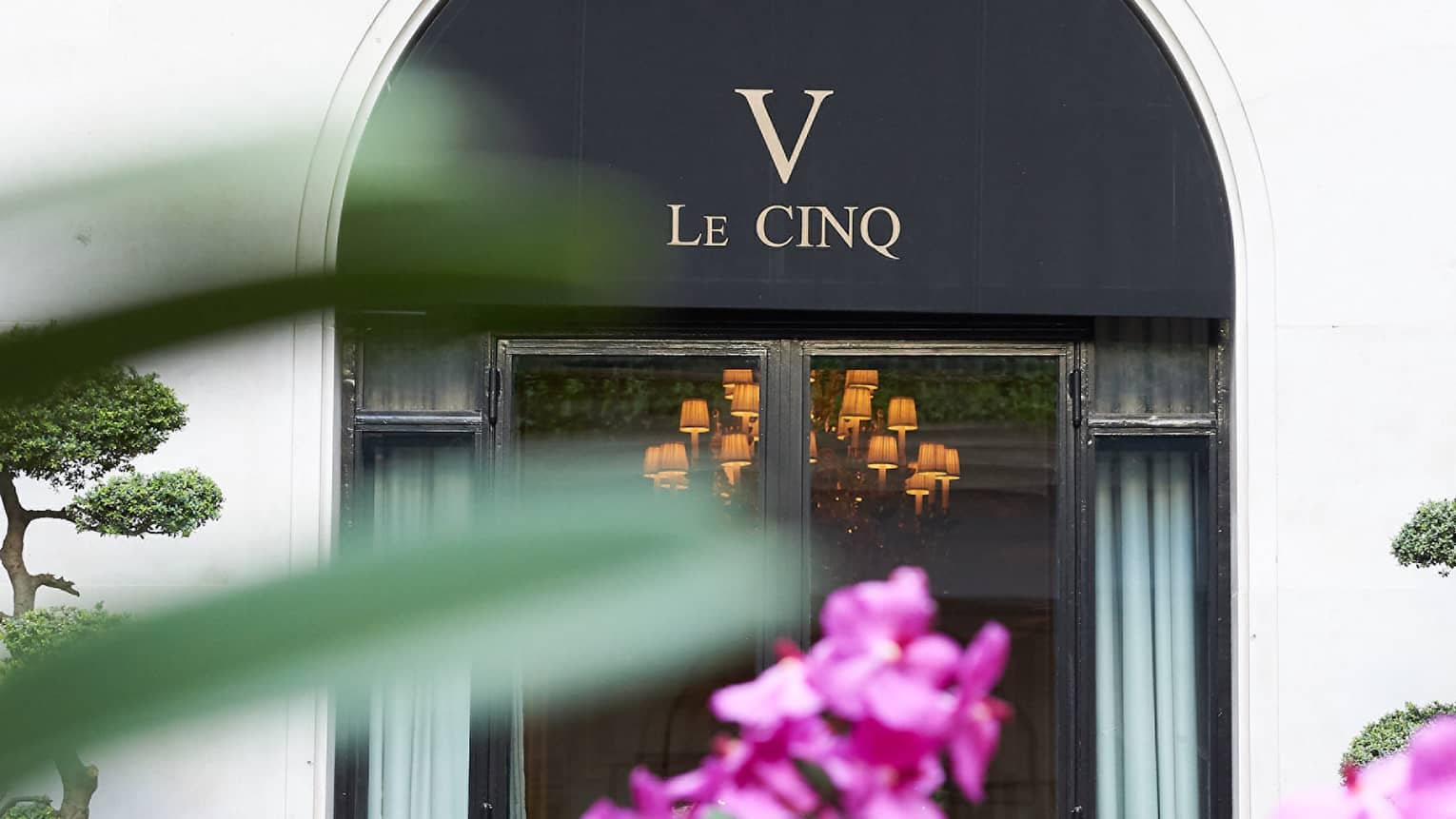 Le Cinq awning over entrance past purple flowers