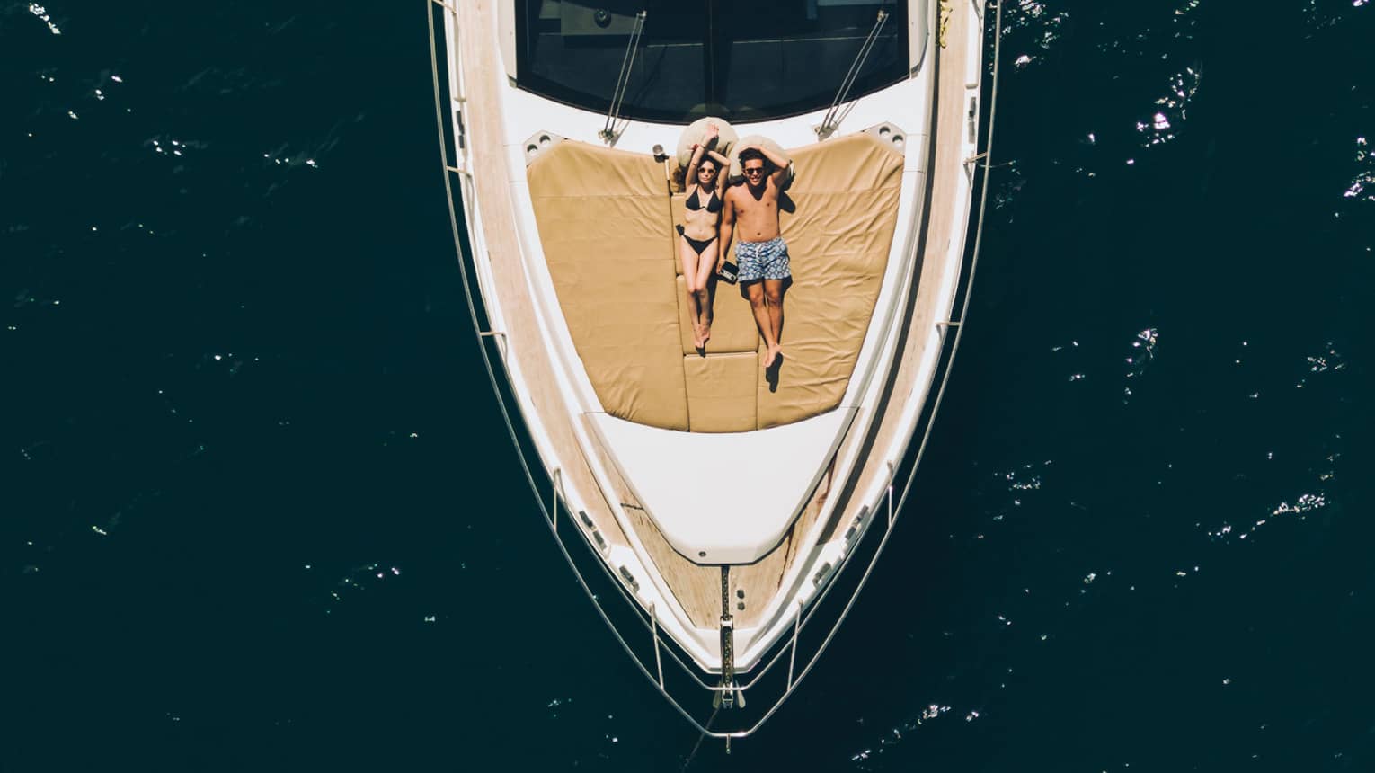 Aerial view of couple relaxing on the front of a large boat