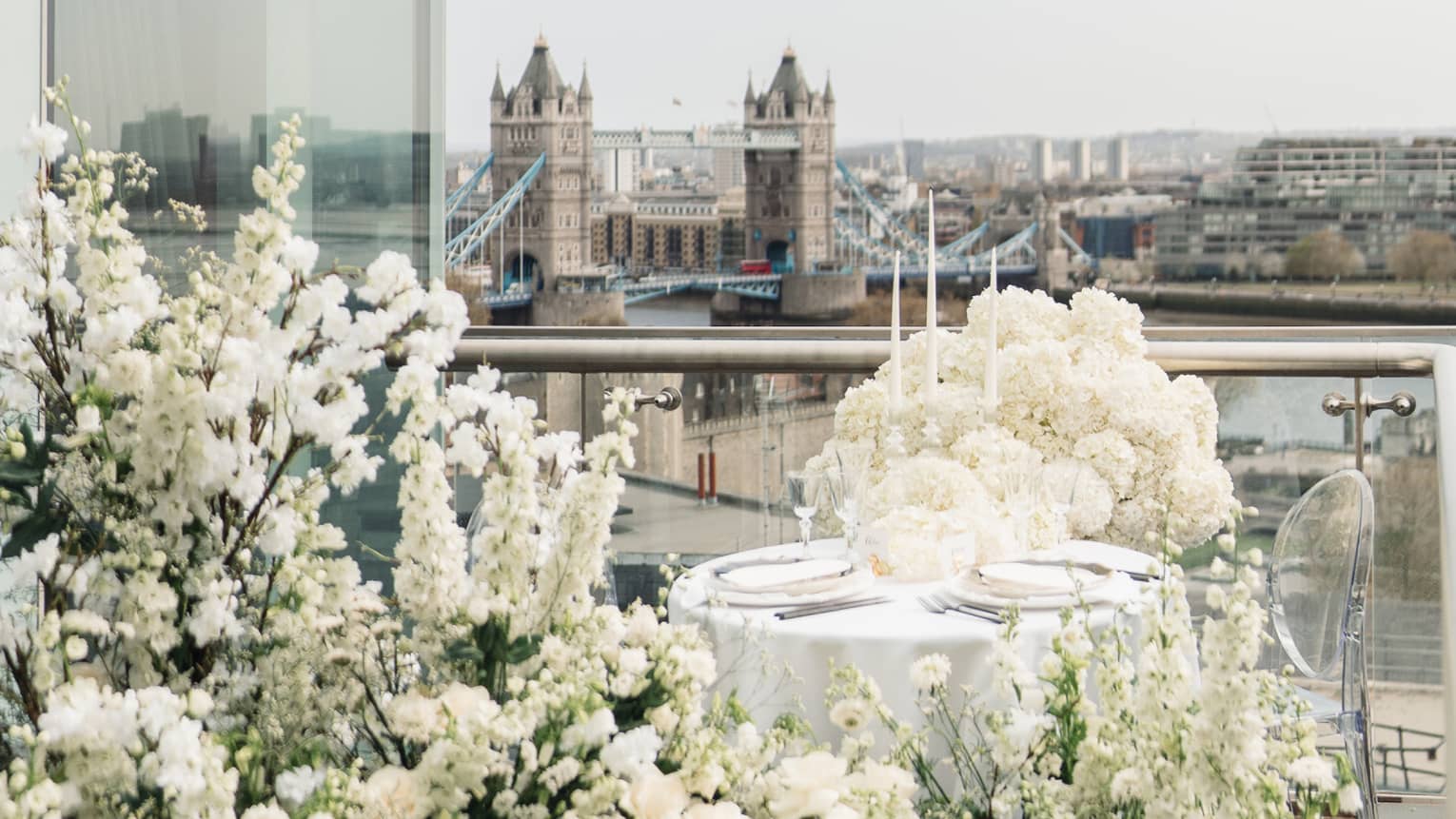 A small table covered and surrounded by white flowers on a terrace.